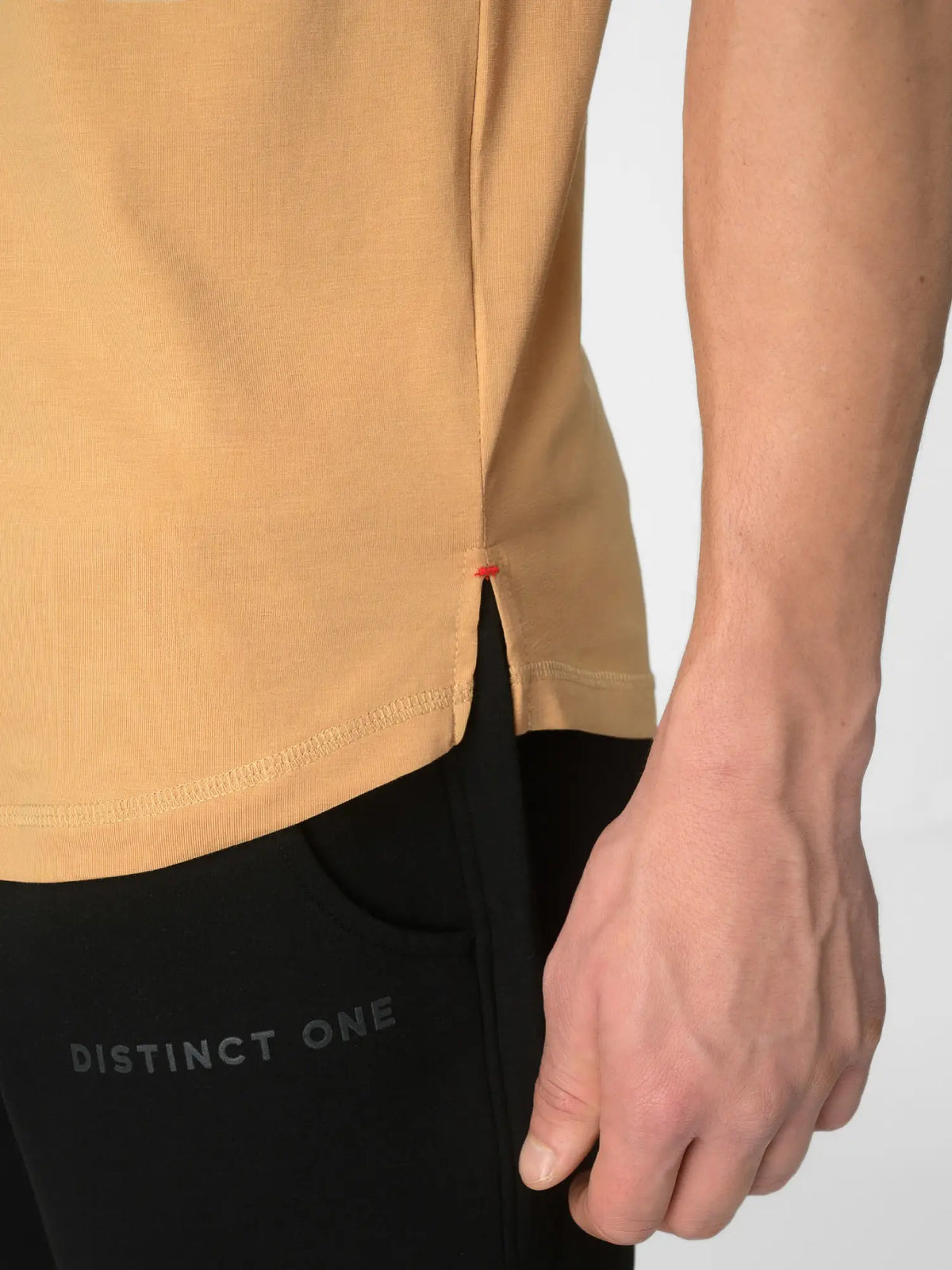 Close-up of a person wearing a mustard yellow top and black leggings with 'DISTINCT ONE' printed on the thigh, against a light gray background.