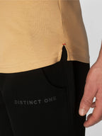 Close-up of a person wearing a tan top and black pants, with the word 'DISTINCT ONE' printed on the thigh and a small red stitch detail at the hem.