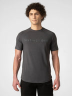 A man wearing a dark gray short-sleeve athletic t-shirt with 'DISTINCT ONE' printed across the chest, paired with black pants, against a light gray studio background.