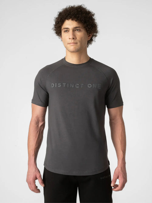 A man wearing a dark gray short-sleeve athletic t-shirt with 'DISTINCT ONE' printed across the chest, paired with black pants, against a light gray studio background.