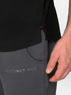 Close-up of a person wearing dark gray Distinct One athletic pants with a side pocket and a black top, showing the brand name on the thigh.