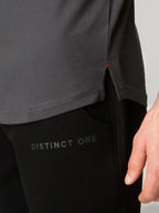 Close-up of a person wearing a dark gray top and black pants with 'DISTINCT ONE' printed on the thigh, against a light gray background.