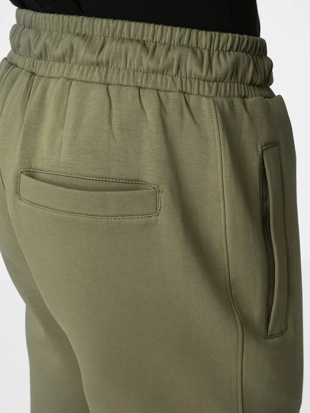 Close-up of olive green sweatpants showing the back pocket, side pocket, and elastic waistband.