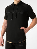 A man wearing a black short-sleeve athletic hoodie with 'DISTINCT ONE' printed across the chest in a subtle dark gray logo, paired with matching black athletic pants against a light gray background.