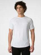 A man wearing a white short-sleeve athletic t-shirt with 'DISTINCT ONE' printed across the chest in a subtle tonal font, paired with black athletic pants, against a light gray studio background.