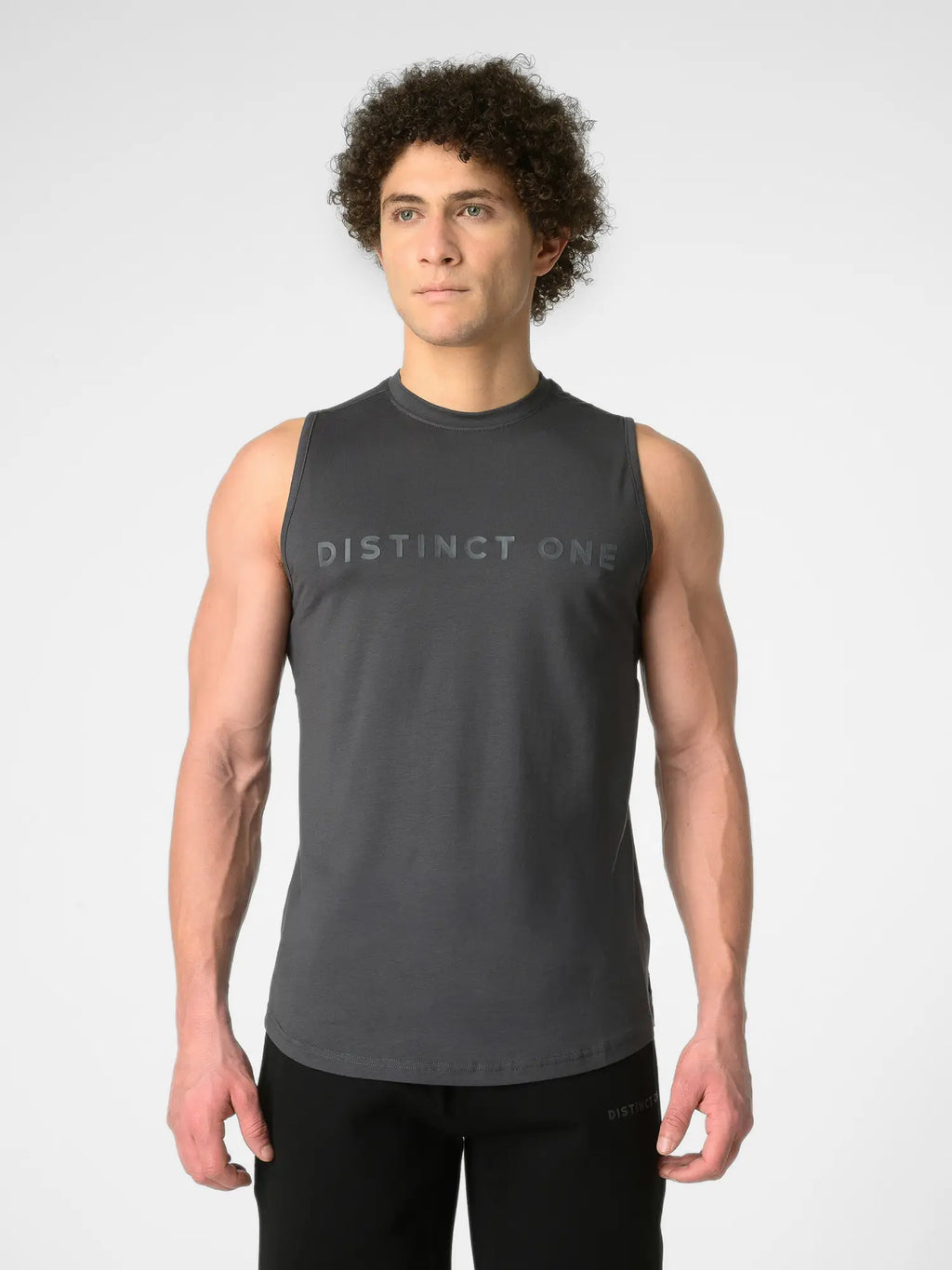 A man wearing a dark gray sleeveless athletic tank top with 'DISTINCT ONE' printed across the chest, paired with black athletic pants, against a light gray studio background.