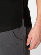 Close-up of a person wearing a black top and dark gray athletic pants with a side pocket and the text 'DISTINGUISH ONE' on the leg.