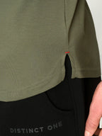 Close-up of a person wearing an olive green short-sleeve top with a side slit, paired with black pants featuring the text 'DISTINCT ONE'.