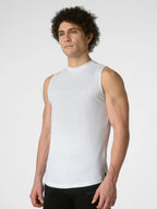 A man wearing a white sleeveless athletic tank top with subtle tonal branding on the chest, paired with black shorts, photographed against a light gray studio background.
