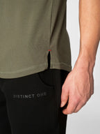 Close-up of a person wearing an olive green athletic top and black pants with 'DISTINCT ONE' printed on the thigh, against a light gray background.