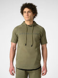 A man wearing an olive green short-sleeve hoodie with 'DISTINCTONE' printed across the chest, paired with matching olive green pants, photographed against a light gray studio background.