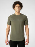 A man wearing an olive green short-sleeve athletic t-shirt with 'DISTINCT ONE' printed across the chest in a subtle, tonal font, paired with black athletic pants, against a light gray studio background.