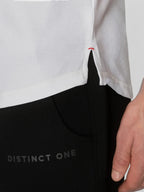 Close-up of a person wearing a white top and black pants with 'DISTINCT ONE' printed on the leg, showing a hand and part of the body.